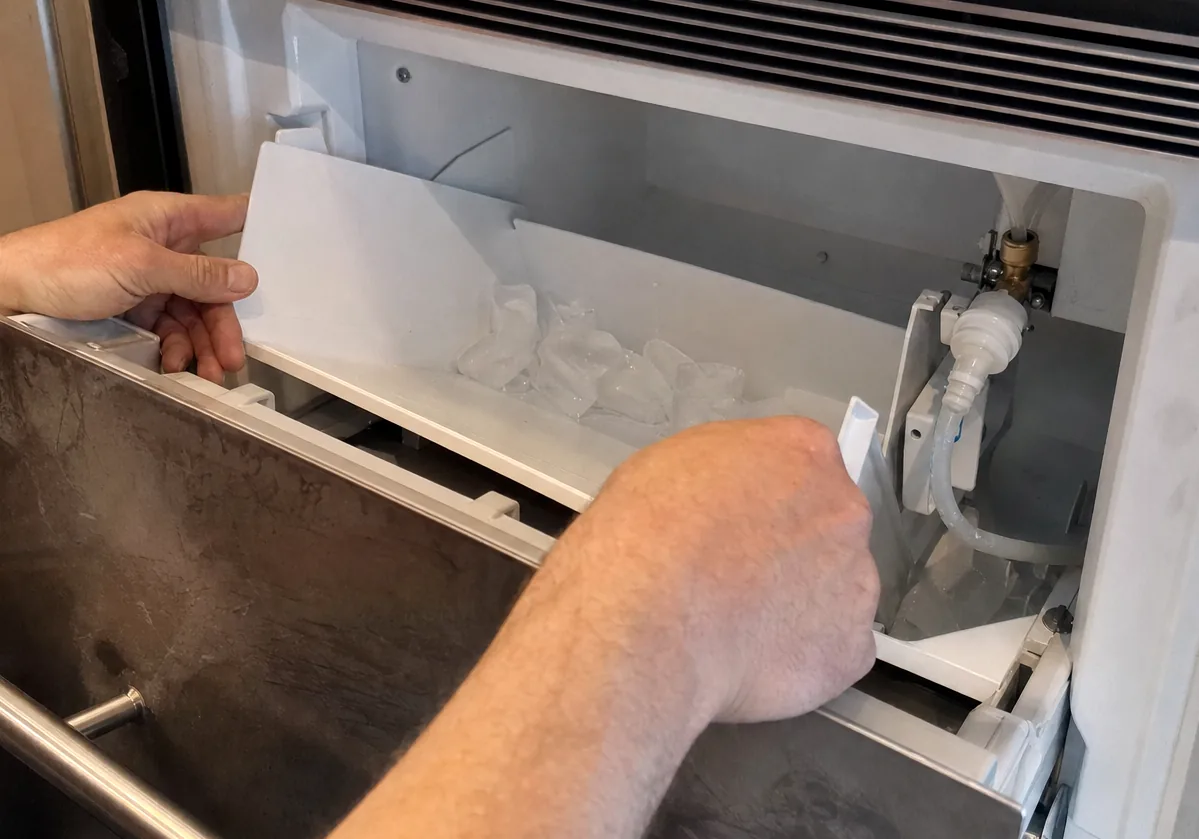 An undercounter unit standing open below the worktop, a bin lifted clear of it.