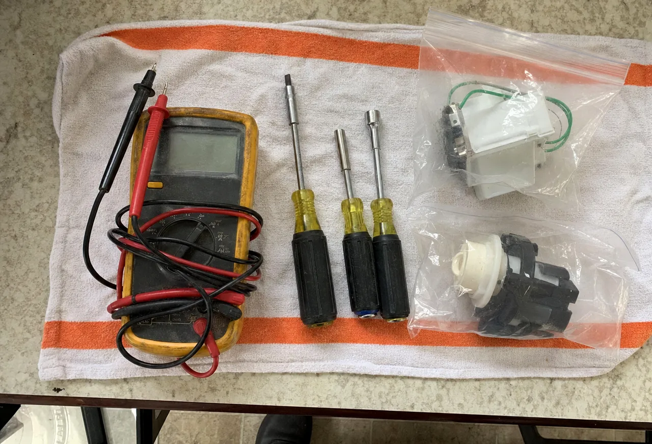 Sealed replacement components in their bags laid out next to hand tools on a towel.