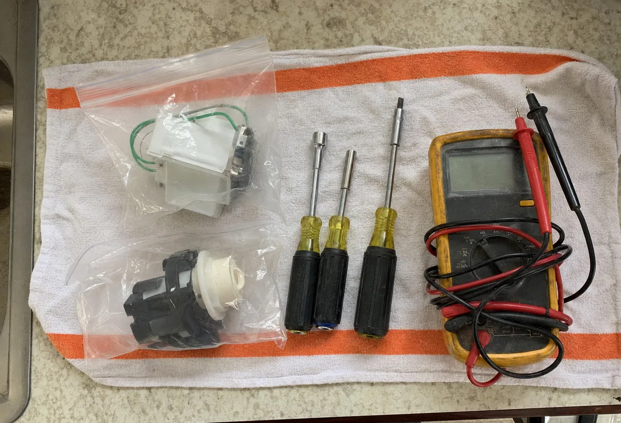 Nut drivers, a meter and two packaged parts set out on a towel at the end of a job.